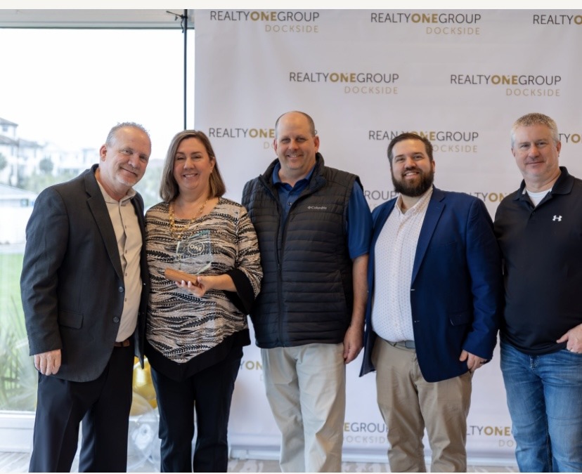 Realty One Group Dockside members celebrate an award presentation, showcasing camaraderie and recognition within the real estate community.
